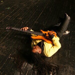 A person laying on the ground holding a guitar