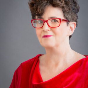 A woman in red is wearing glasses and posing for the camera.